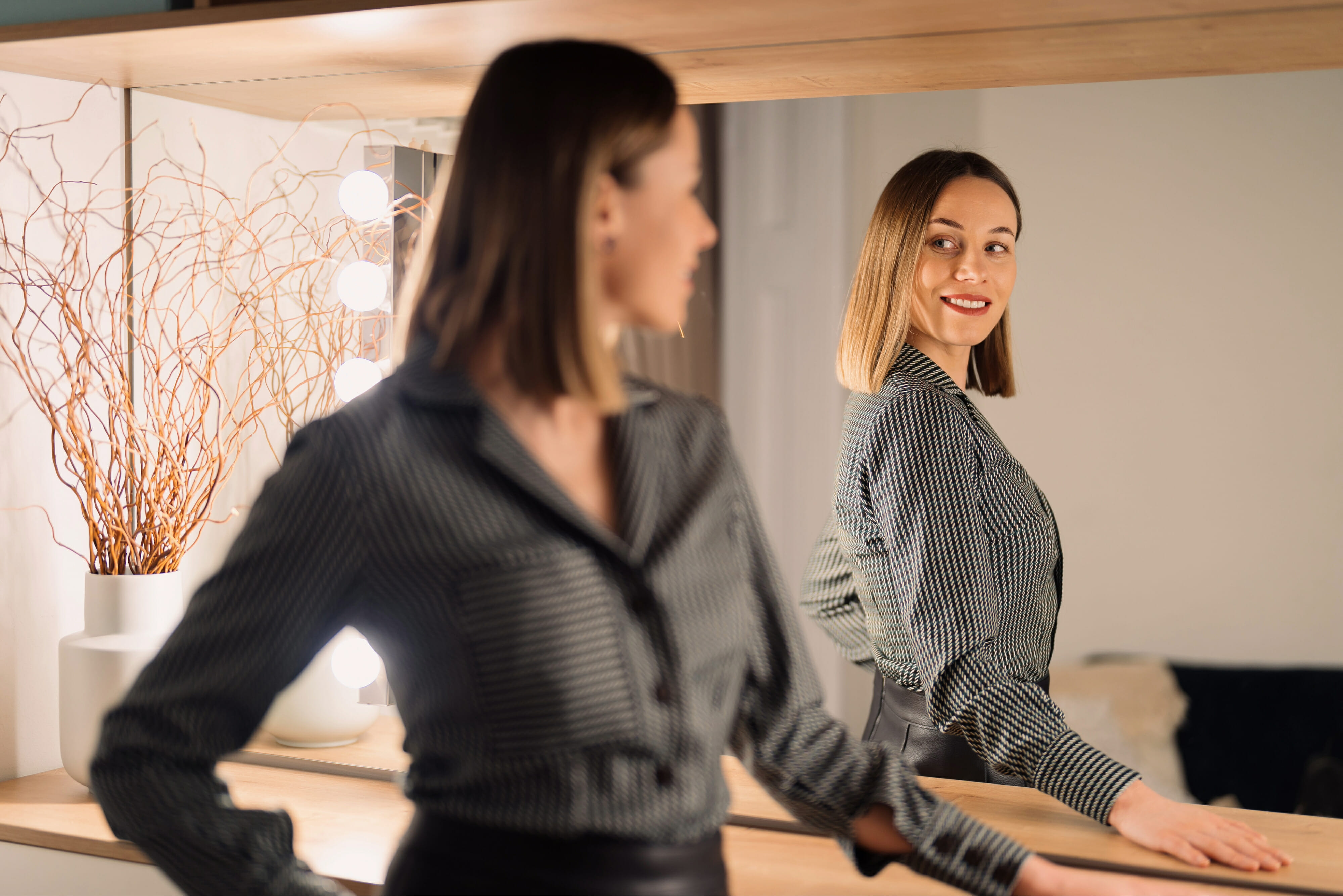Self-confident woman looking at her reflection into the mirror indoors