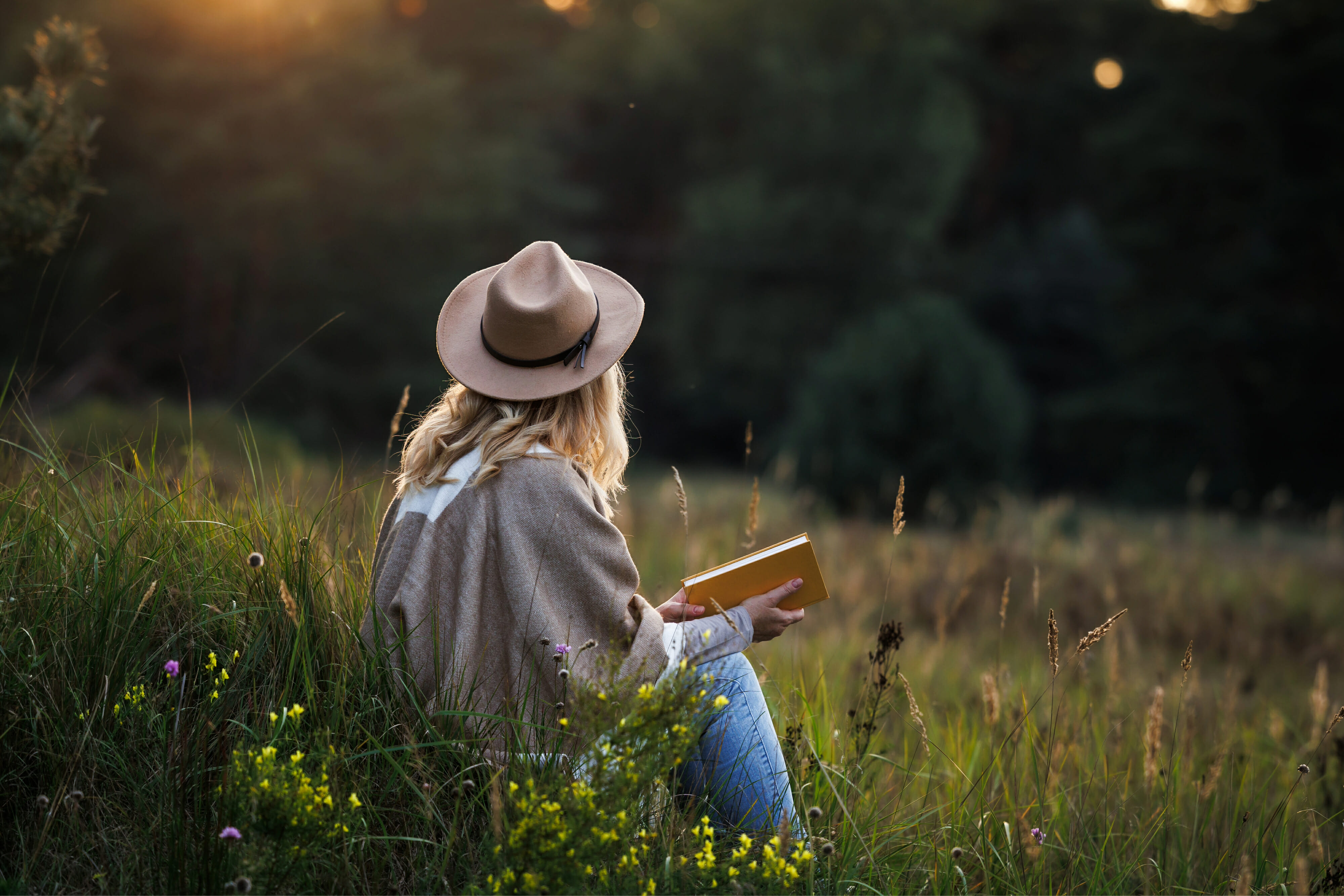 Woman is relaxing in nature and reading a book to improve her mindfulness and mental health