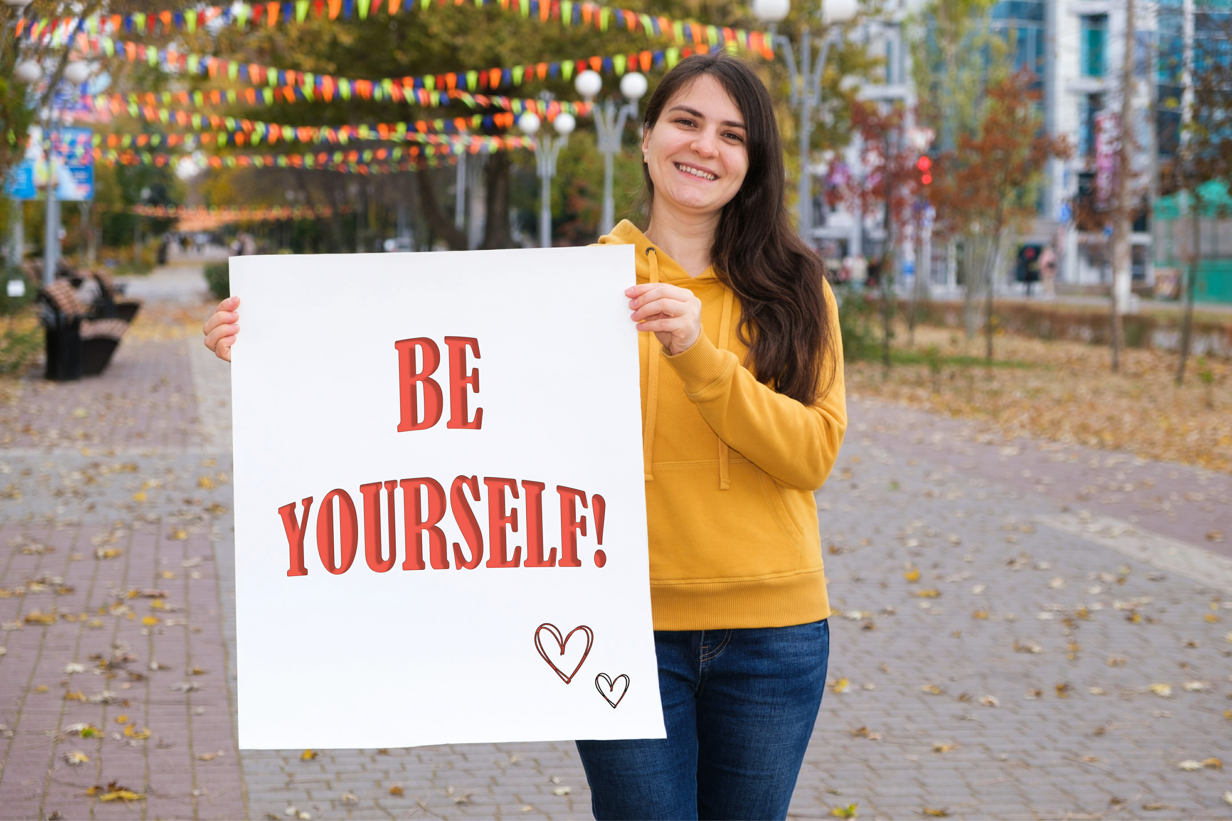 A woman holds a poster with a sign on white Be yourself