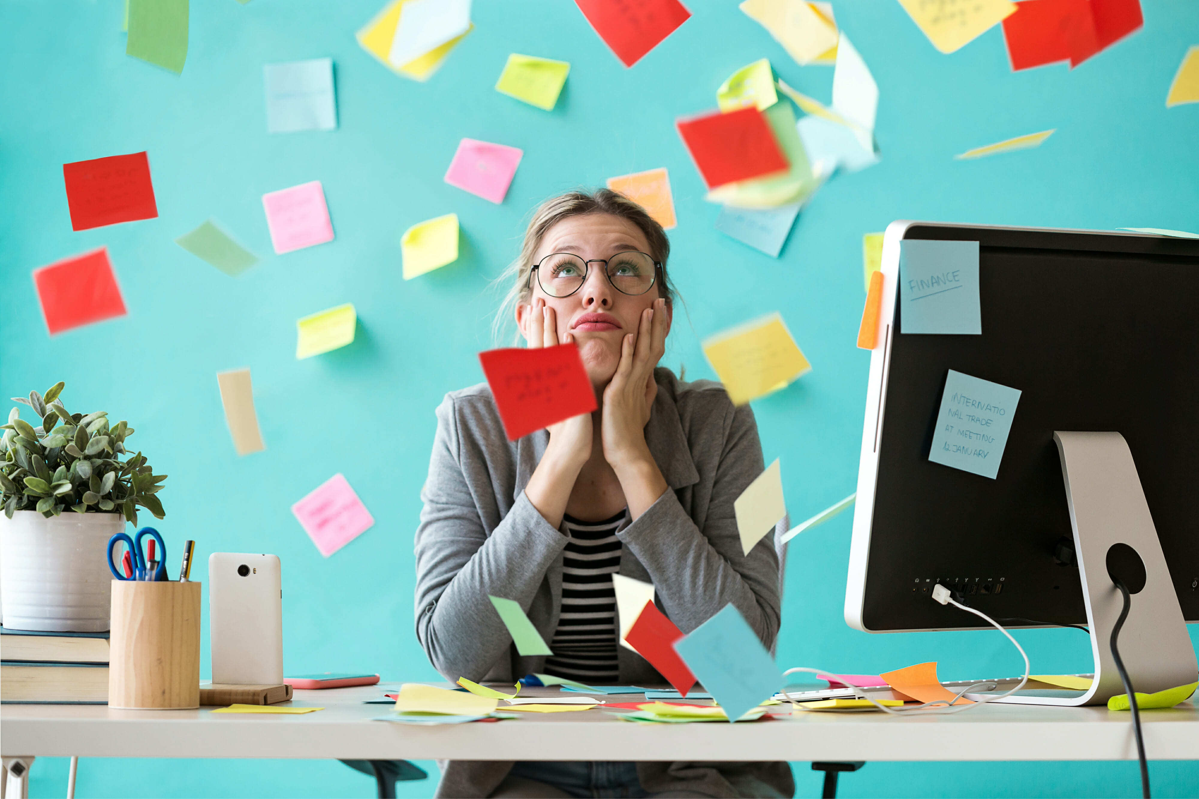 Stressed young business woman looking up surrounded by post-its in the office