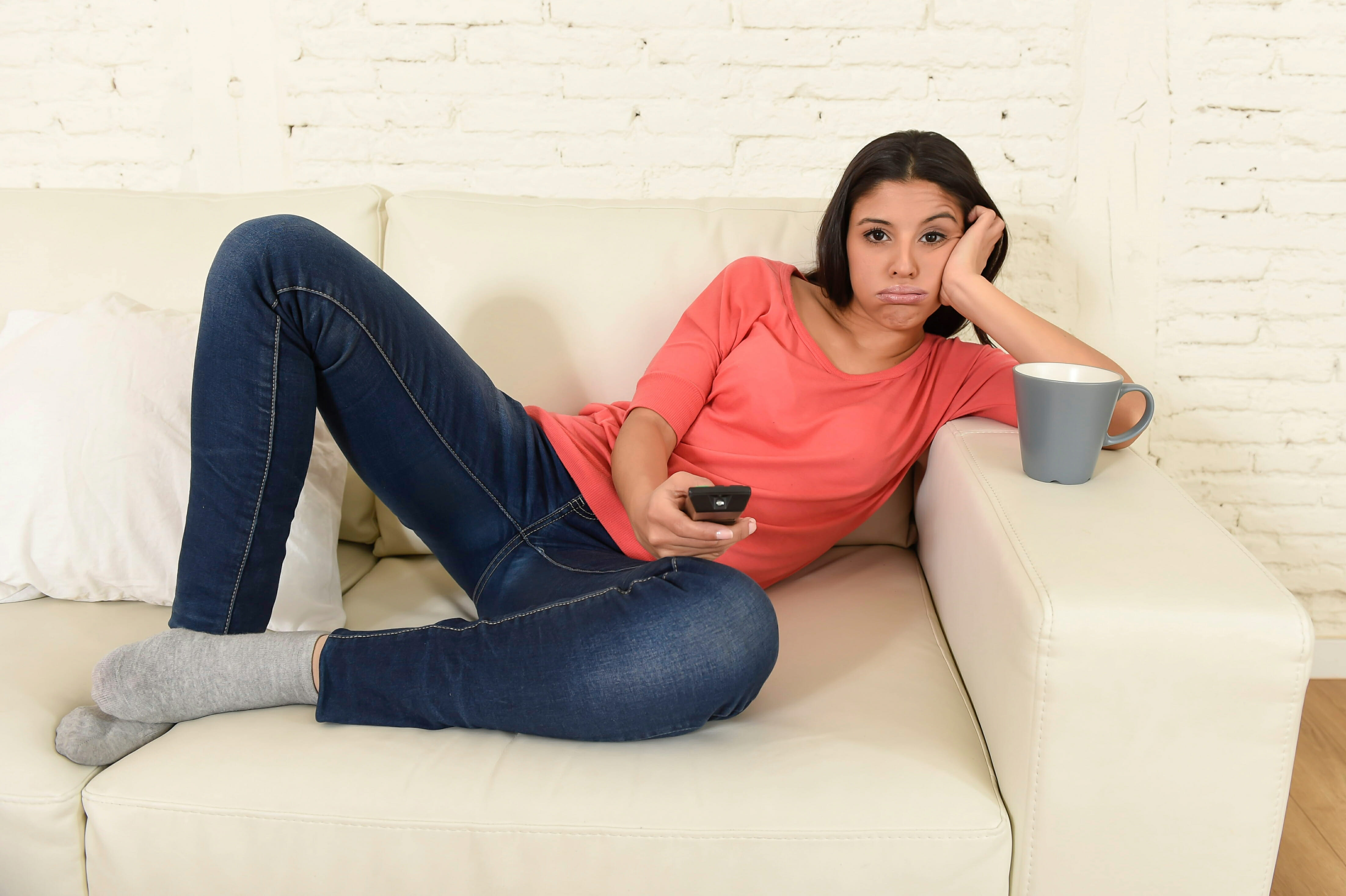 Young beautiful hispanic woman at home watching television tired and bored