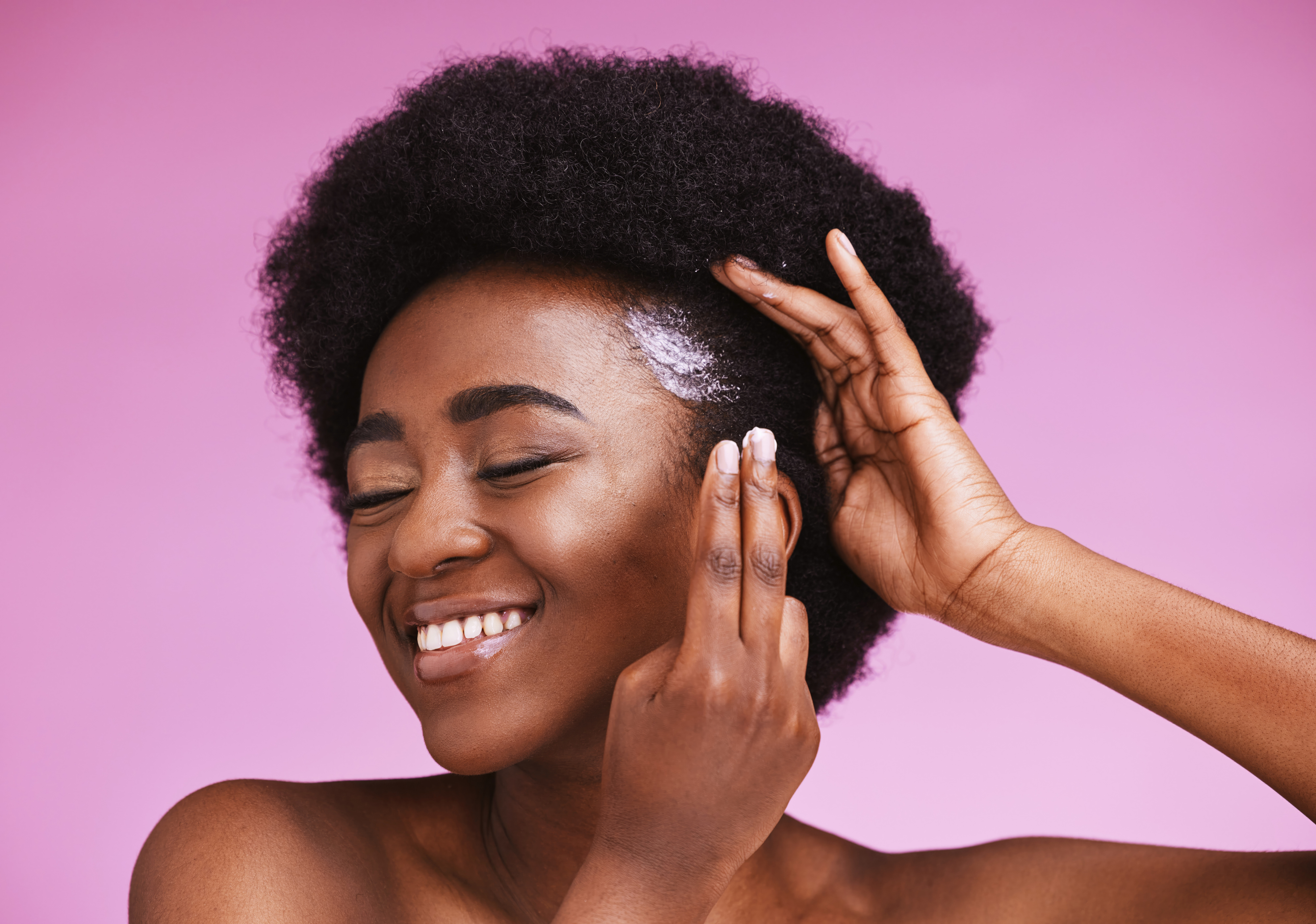 Happy black woman, afro hair and conditioner treatment for ethnic texture on pink studio background