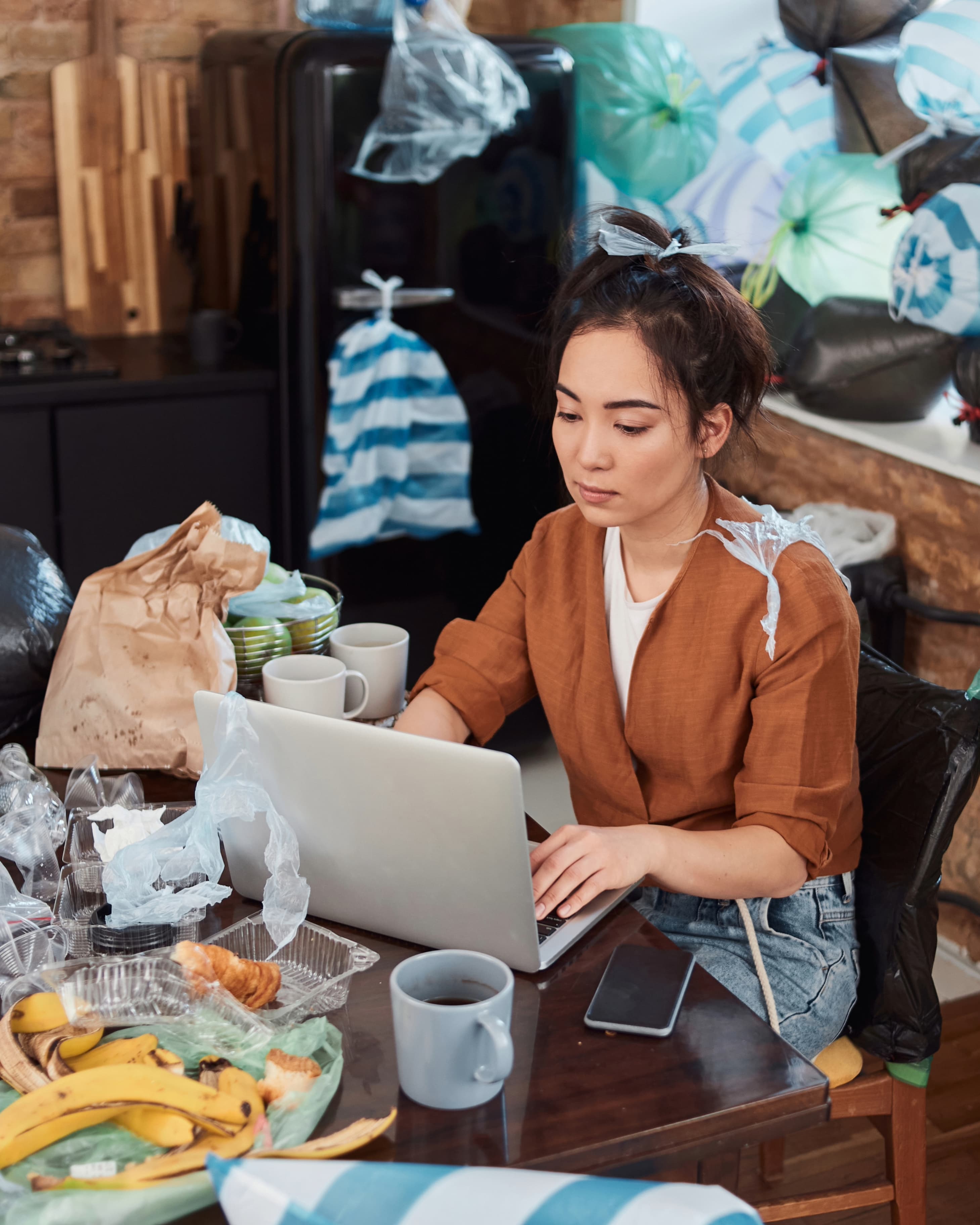 Concentrated woman working online in a messy flat