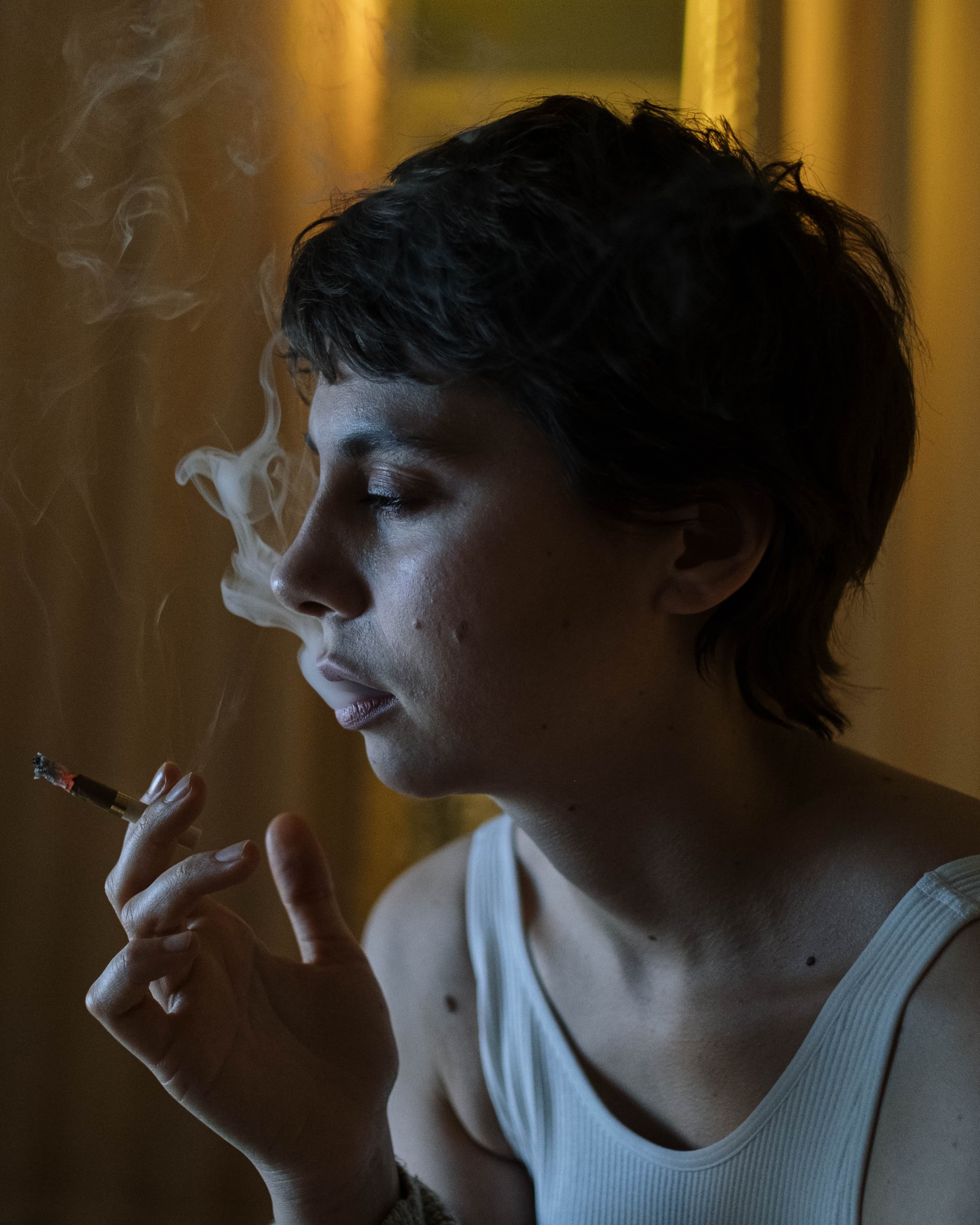 Photo of a woman with short hair smoking a cigarette