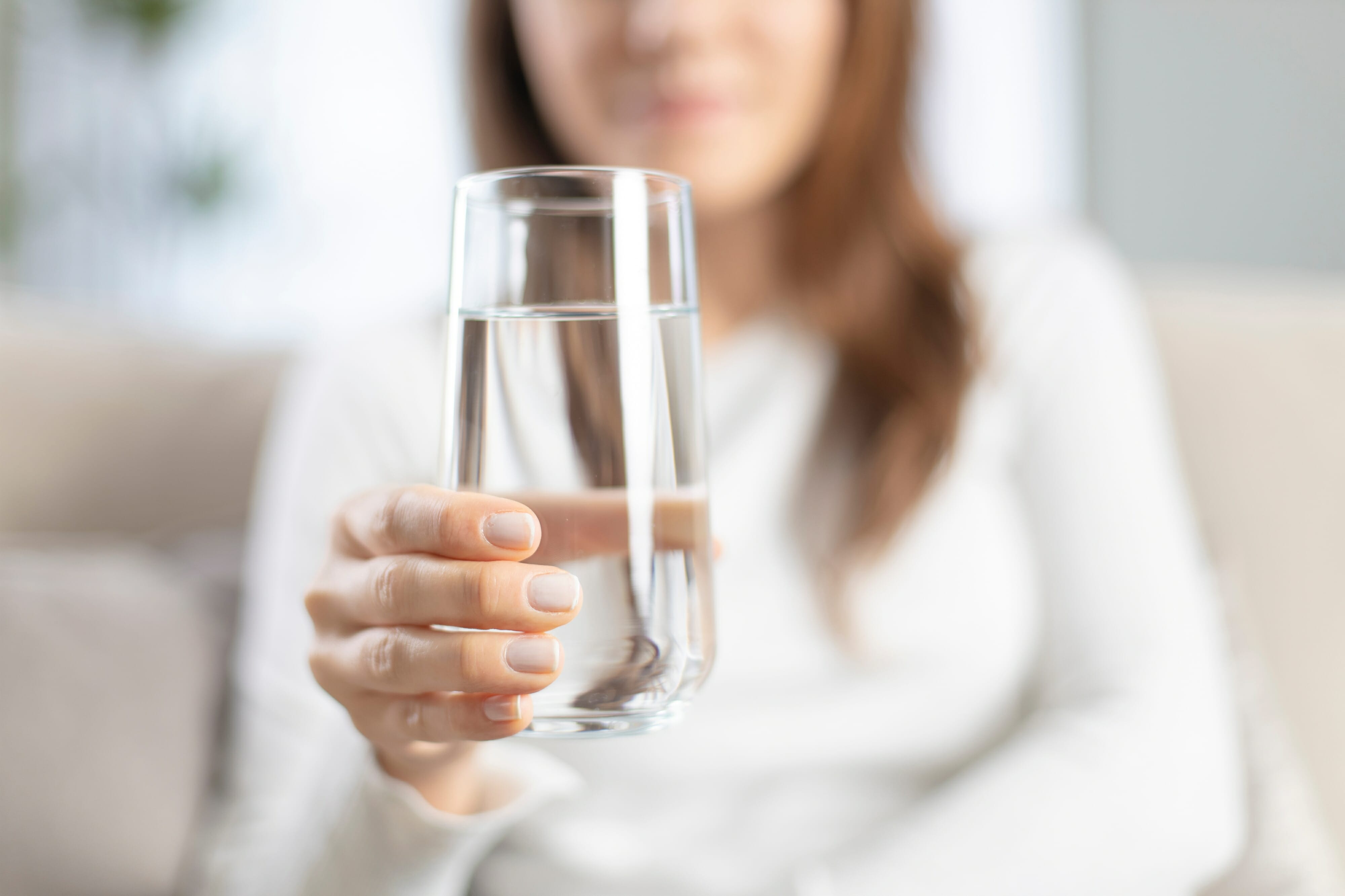 Close-up image of a woman holding a glass of mineral water