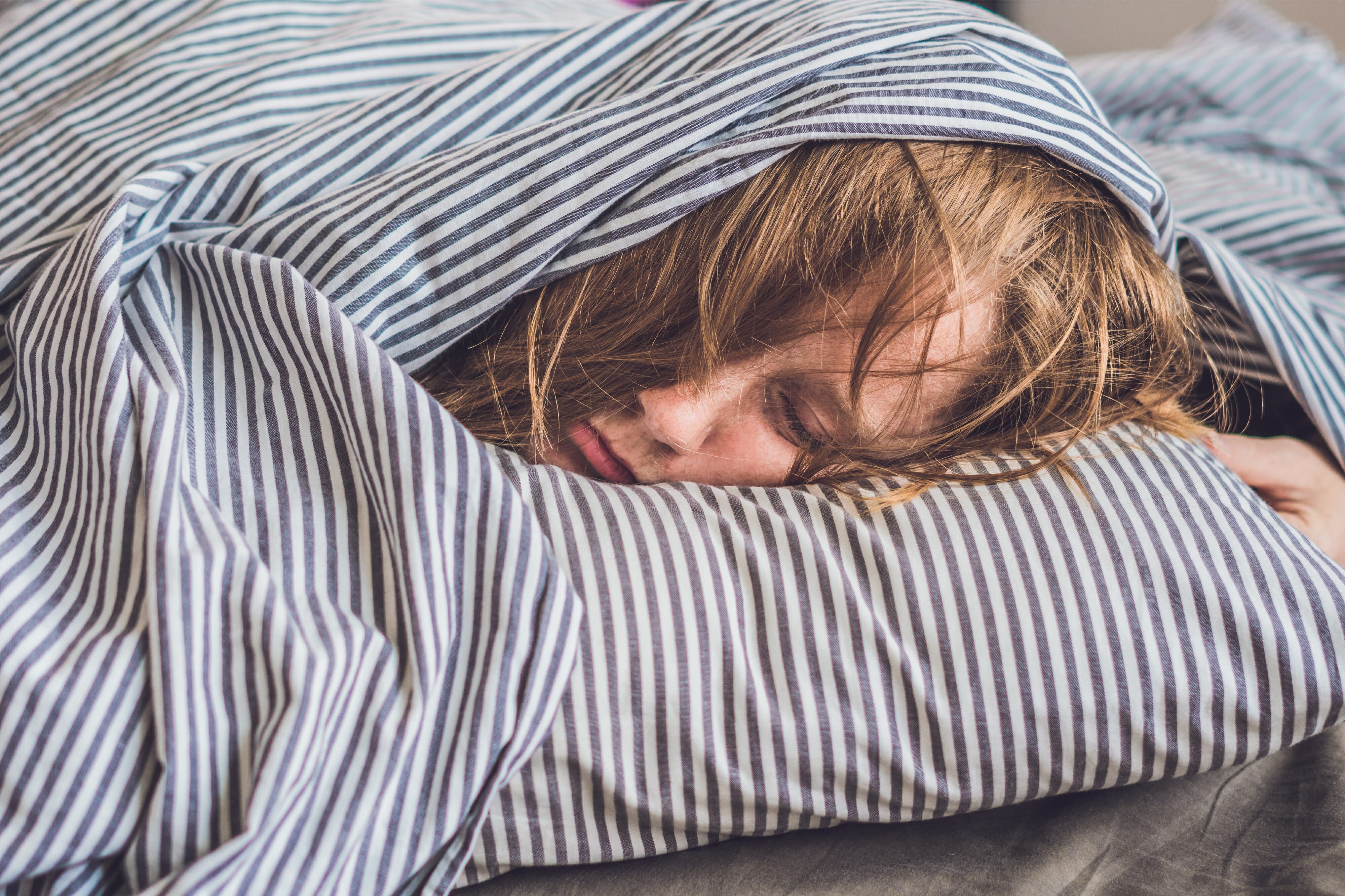 A beautiful young woman lies down in bed and does not get enough sleep