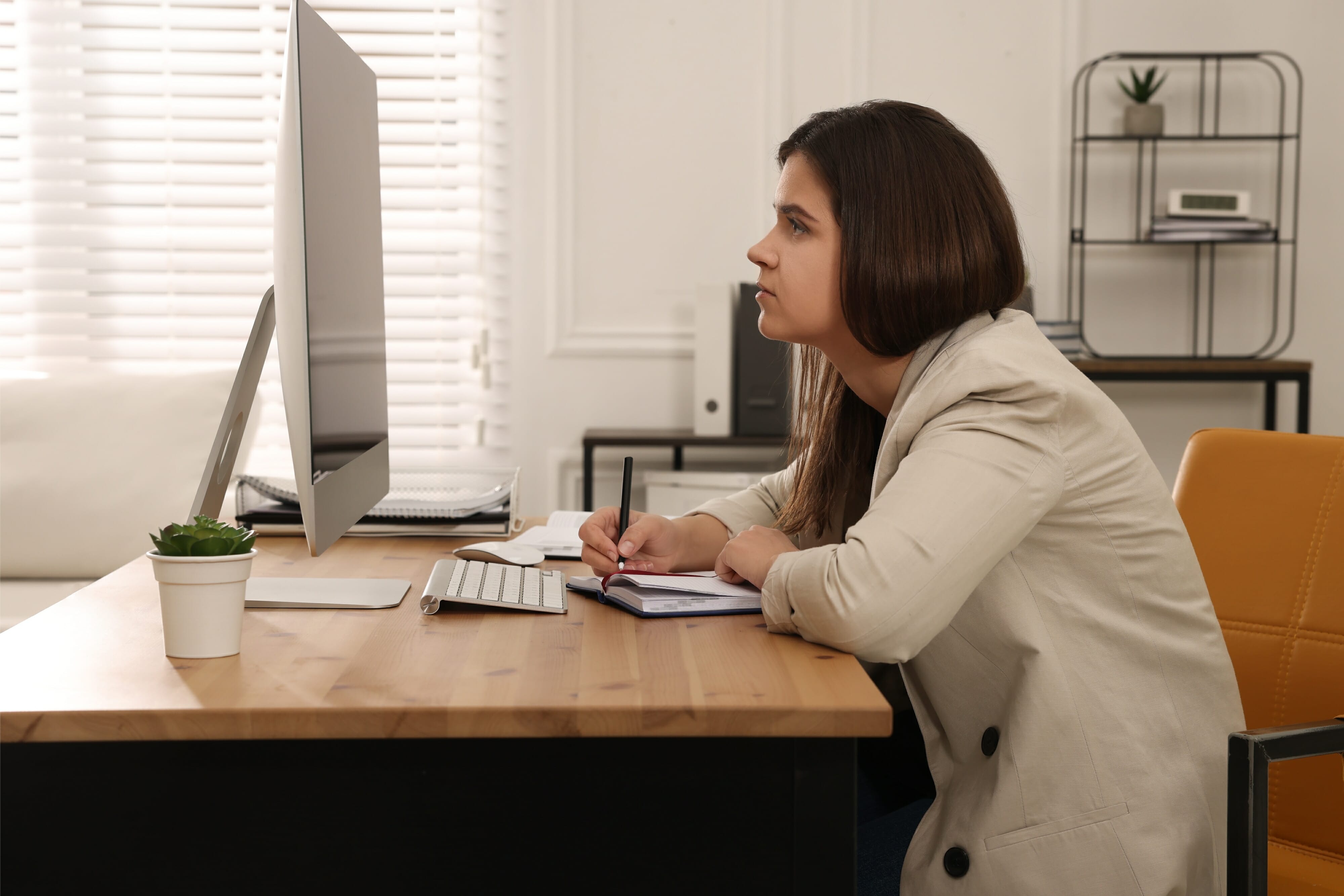 Young woman with bad posture working on computer in office